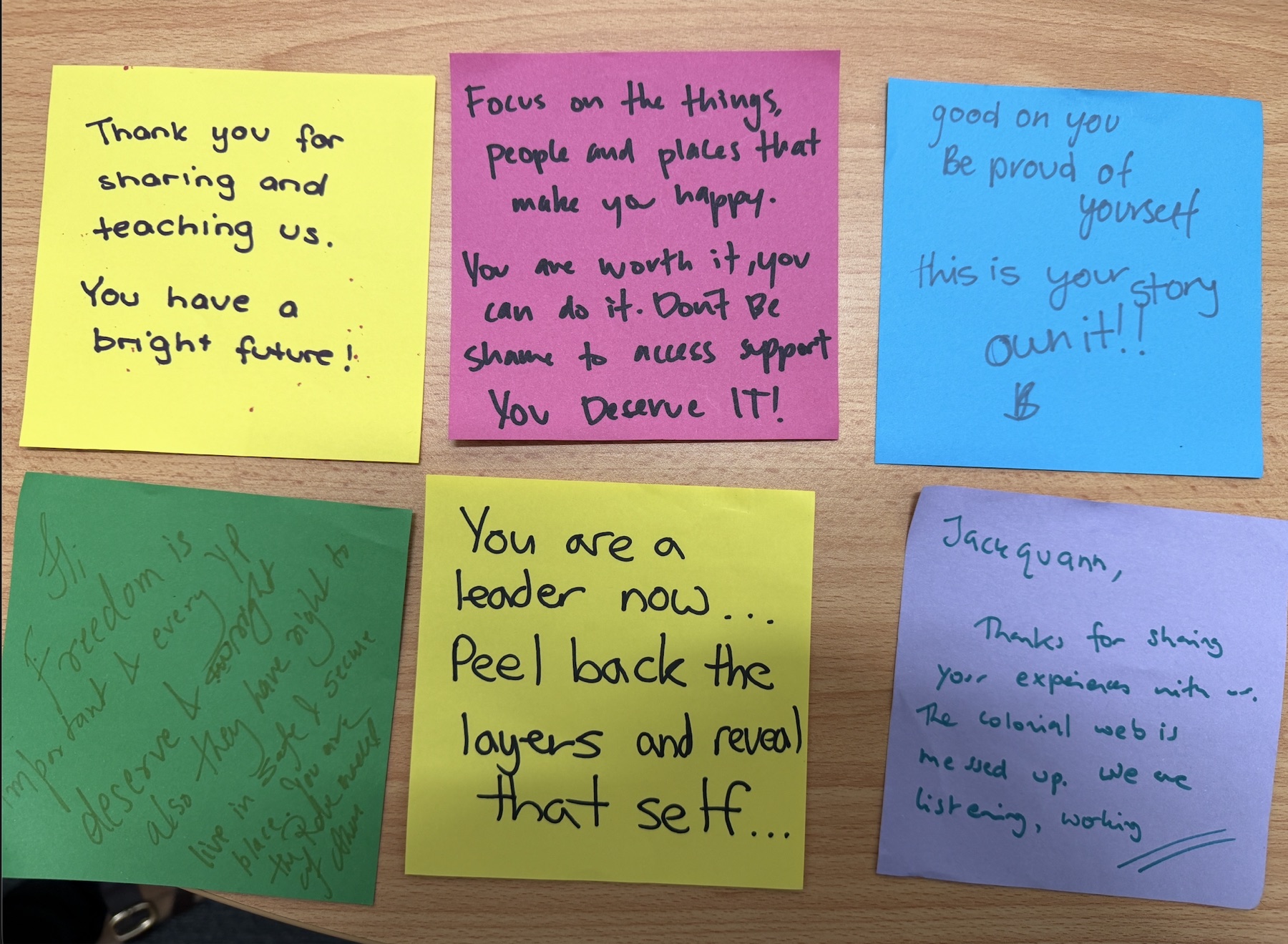 Six handwritten notes on coloured paper on a wooden table, including “Thank you for sharing and teaching us. You have a bright future!” and “You are a leader now. Peel back the layers and reveal that self.”