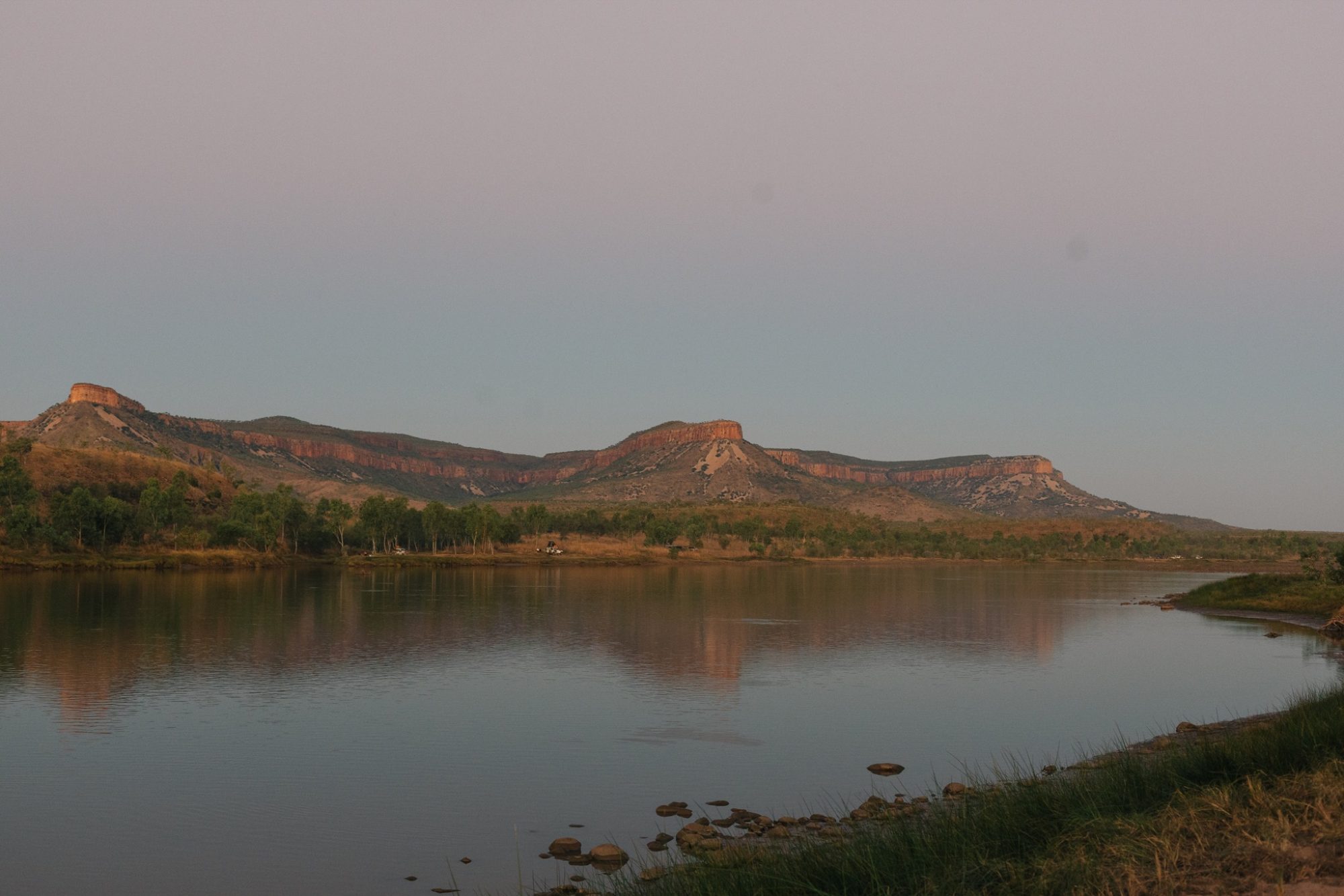 A wide river at dusk with a range behind it, on Country in the East Kimberley.
